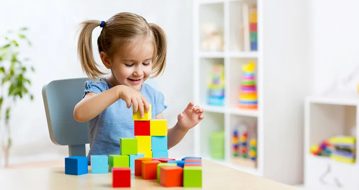 A cute kid is building blocks with full concentration.